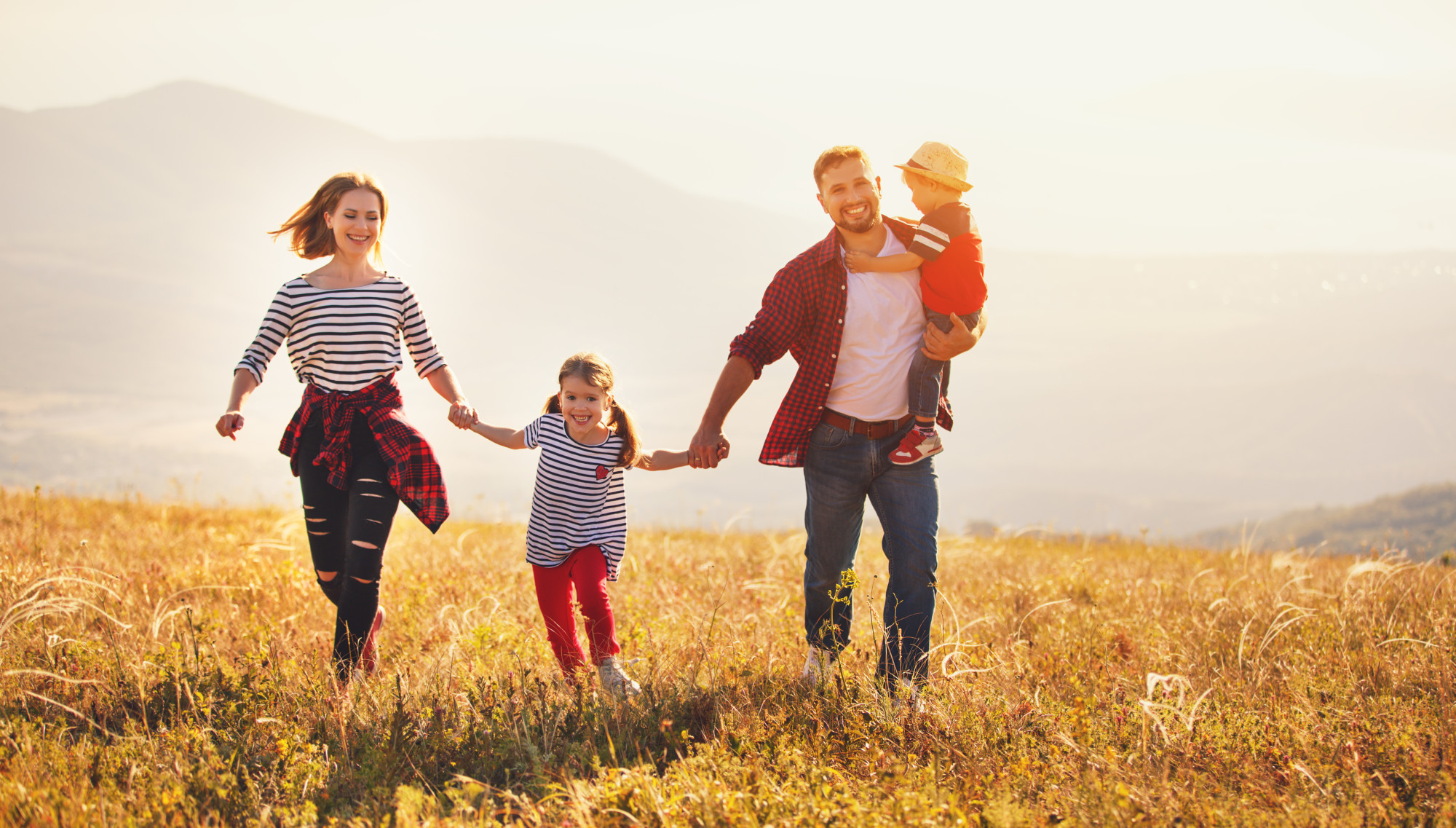 Glueckliche Familie laeuft ueber eine Wiese HAIDER BIOSWING